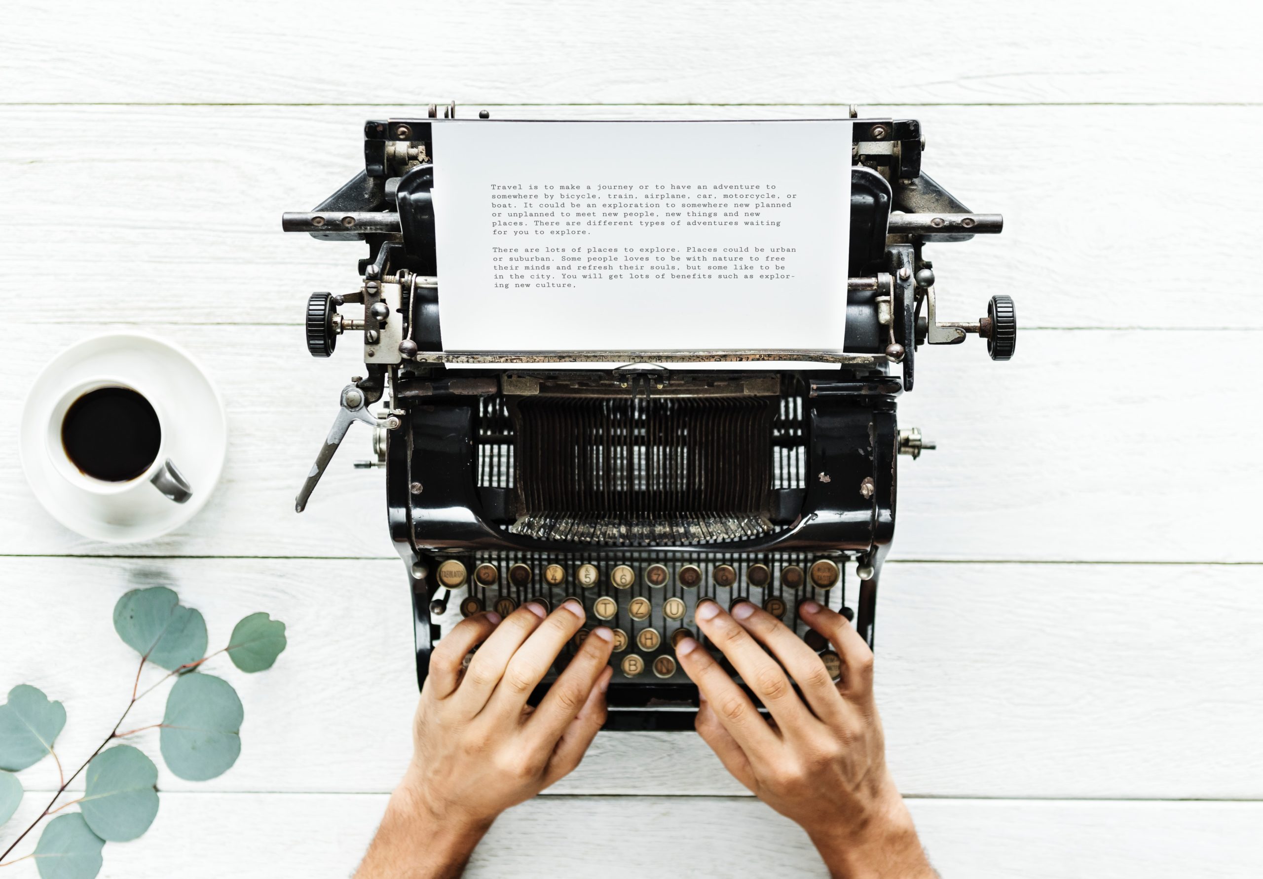 Schreibmaschine Person schreibt Hände Pflanze Kaffee weisser Tisch