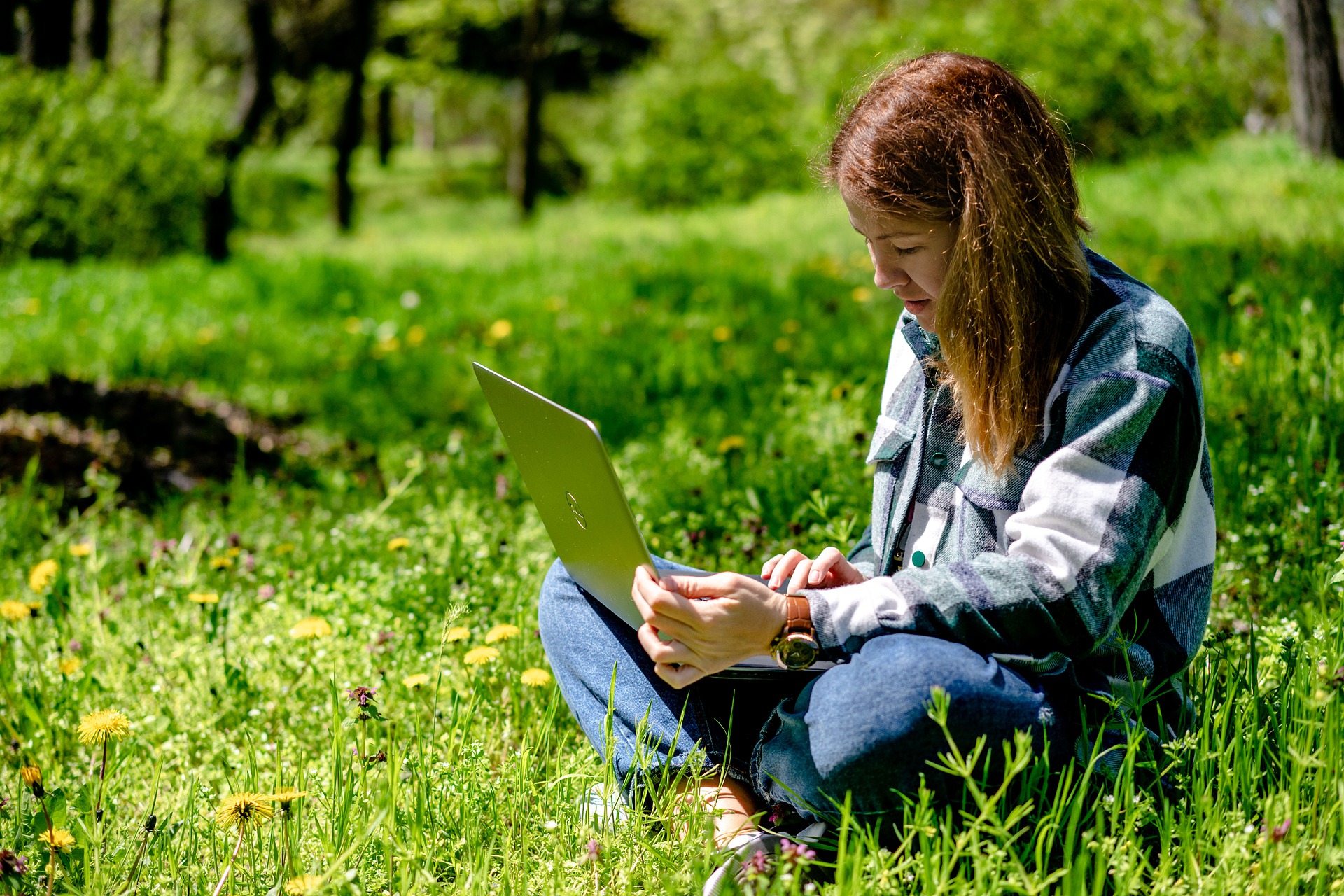 Frau sitzen mit Laptop in der Natur